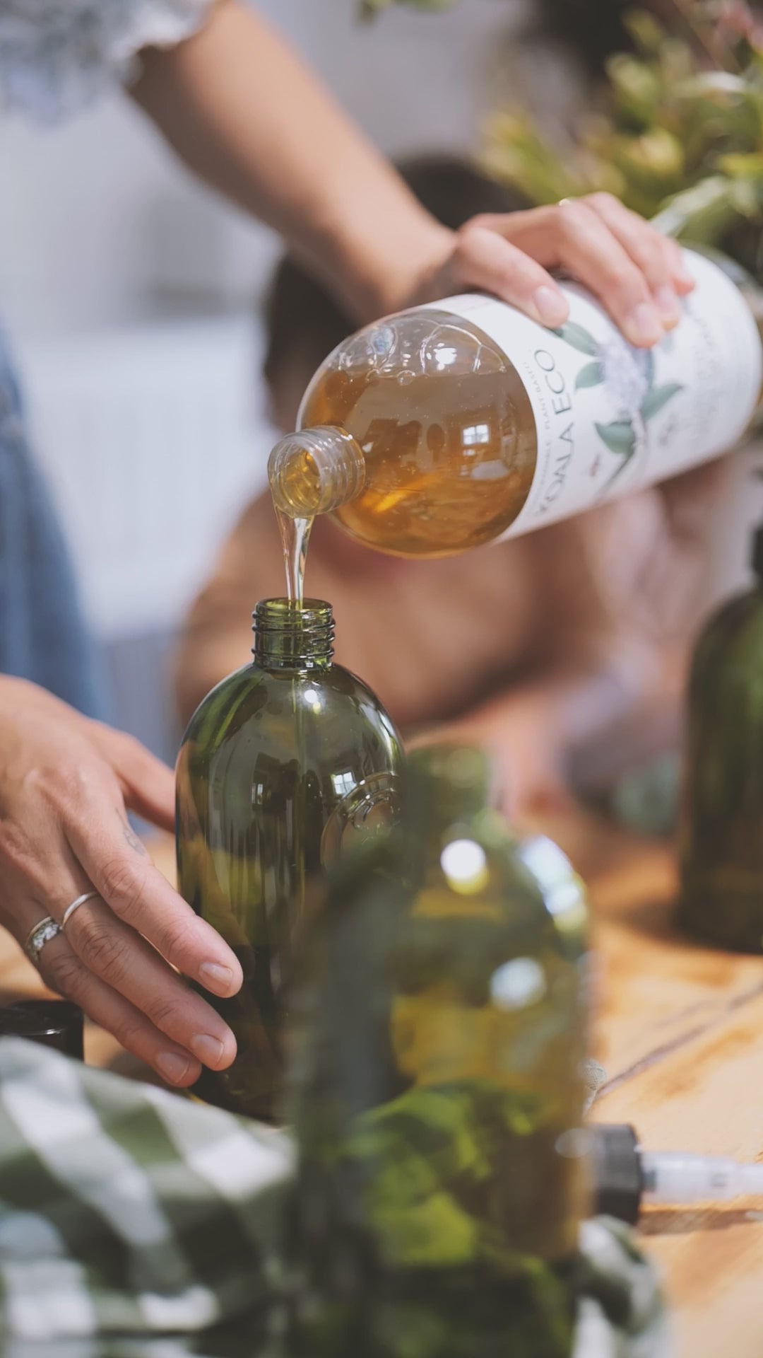 A woman refilling a glass bottle with koala Eco hand wash